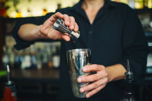 Barman versa un distillato nello shaker per la preparazione di un cocktail